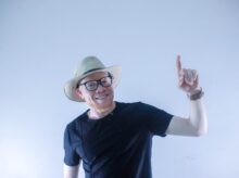 man in black crew neck t-shirt wearing green hat and eyeglasses