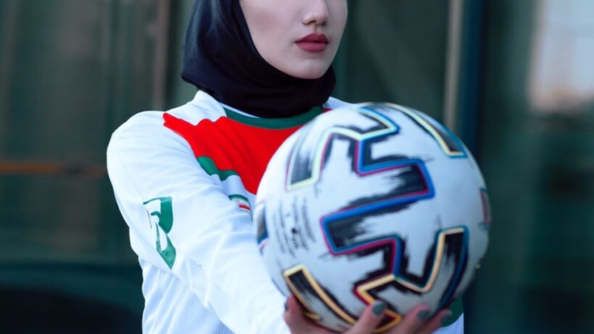 woman in white and blue long sleeve shirt holding white and black nike soccer ball
