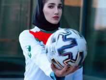 woman in white and blue long sleeve shirt holding white and black nike soccer ball