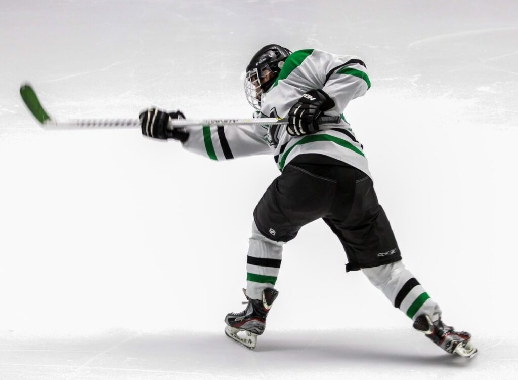 man wearing green and white ice hockey jersey while playing