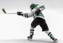 man wearing green and white ice hockey jersey while playing