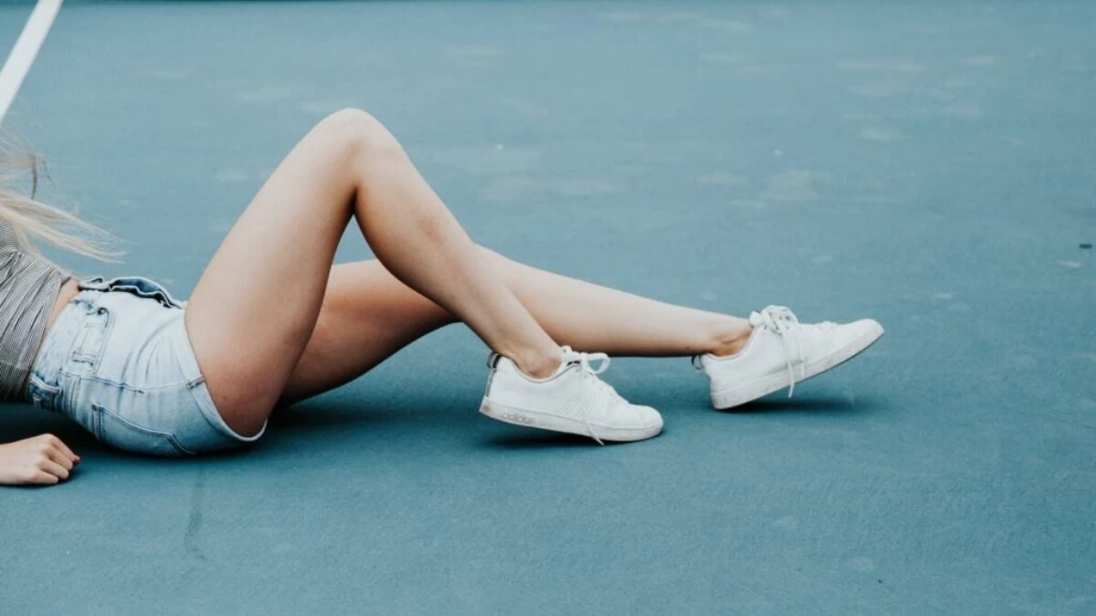 woman lying on tennis court floor during daytime