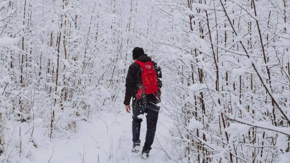 man in black jacket walking on snow covered ground during daytime