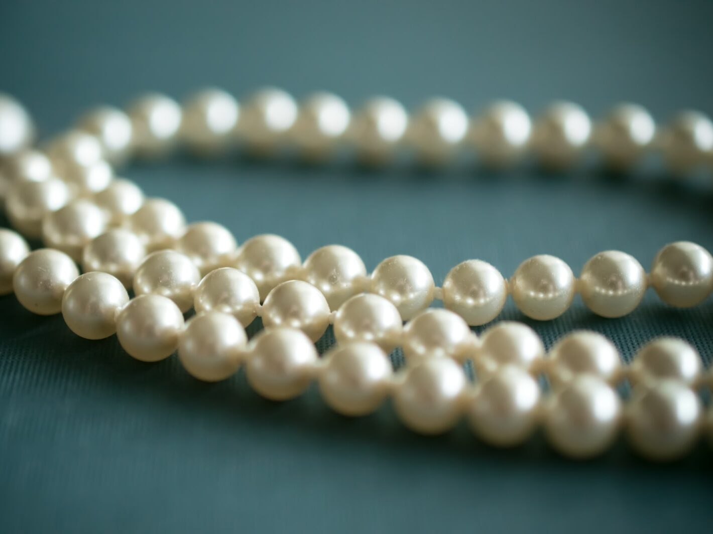 white pearl necklace on gray textile