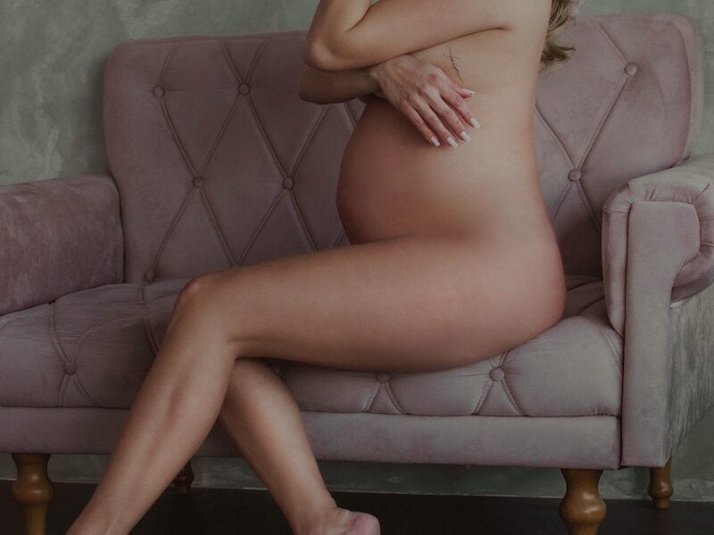 Naked Pregnant Woman Sitting on Pink Couch