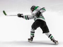man wearing green and white ice hockey jersey while playing