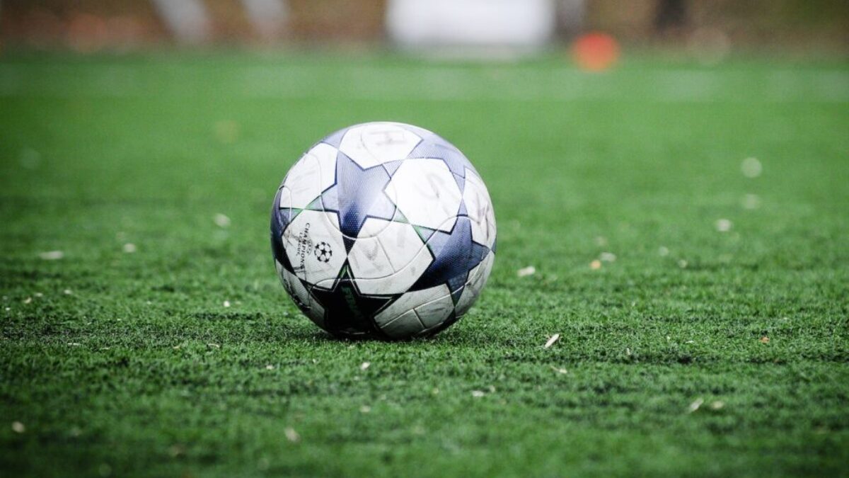 white and blue soccer ball on green grass field during daytime