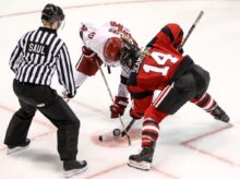 two persons playing ice hockey with referee