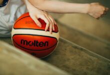 person holding red and white Molten basketball ball