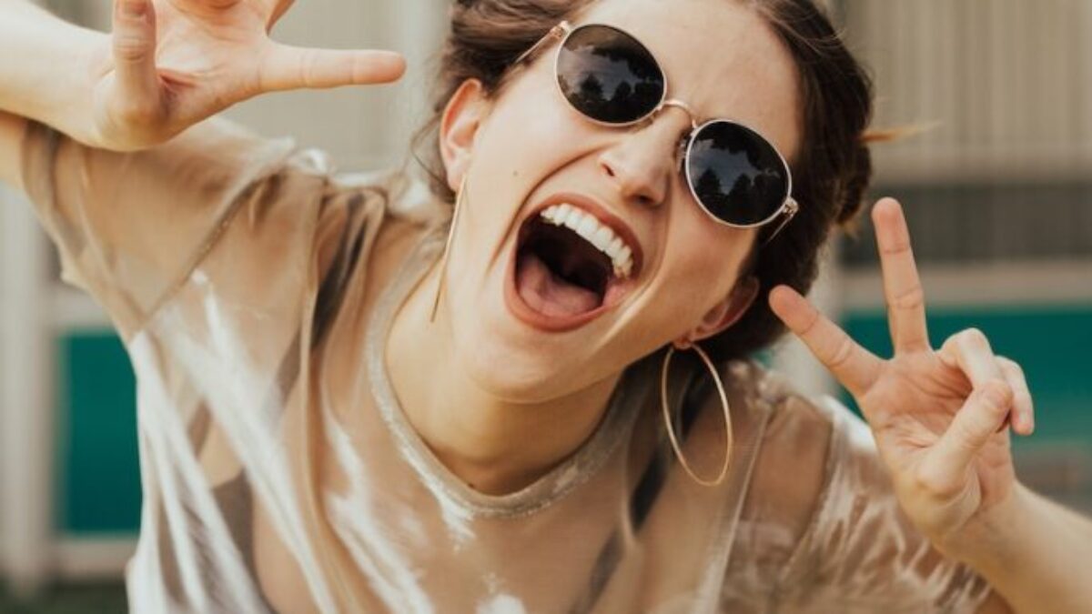 selective focus photography of jolly woman using peace hand gesture