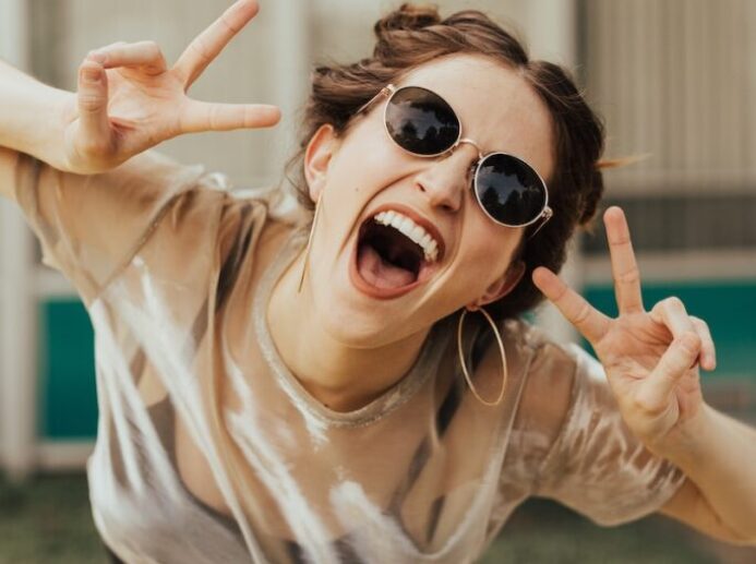 selective focus photography of jolly woman using peace hand gesture