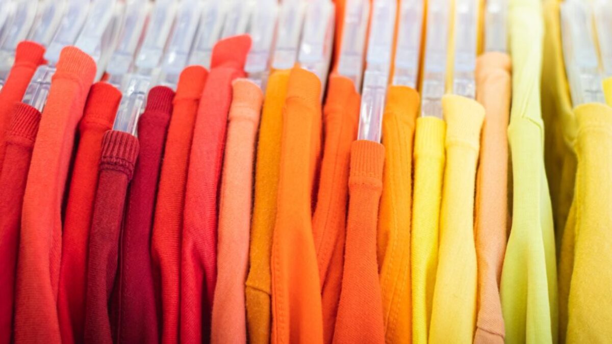 a bunch of different colored shirts hanging on a rack