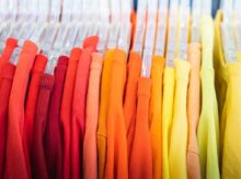 a bunch of different colored shirts hanging on a rack