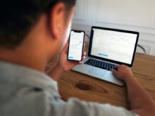 man in gray hoodie holding black smartphone