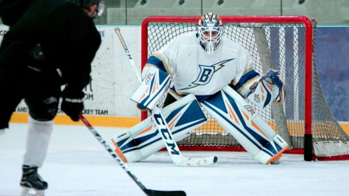 man taking aim for goal on hockey goalie