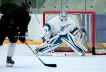 man taking aim for goal on hockey goalie