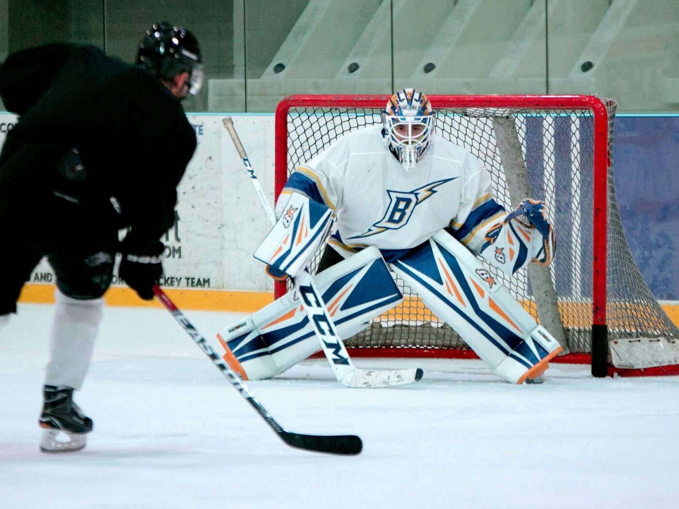 man taking aim for goal on hockey goalie