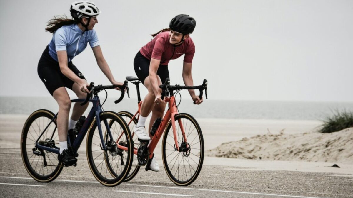 man and woman riding road bikes at the road near shore