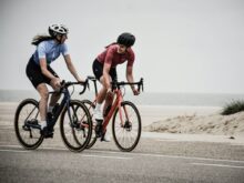 man and woman riding road bikes at the road near shore