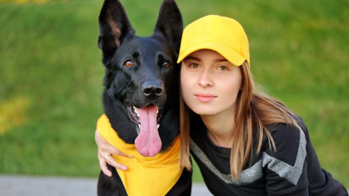 Dívka ze žluté kšiltovce drží kolem krku psa se žlutým šátkem