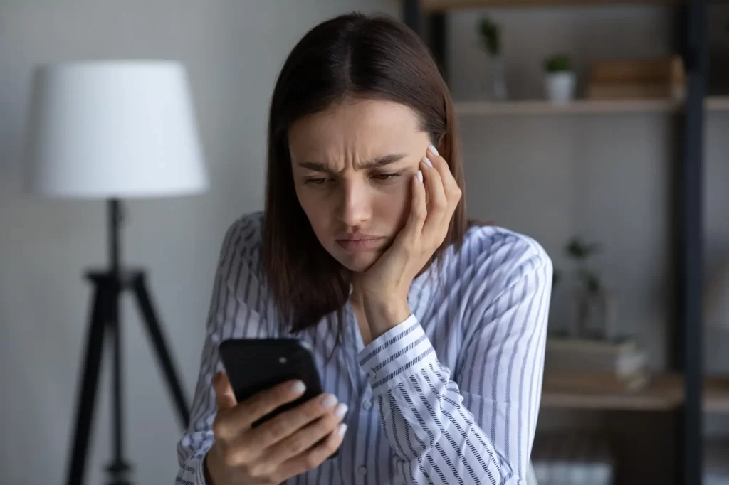 Zamračená žena kouká na telefon 