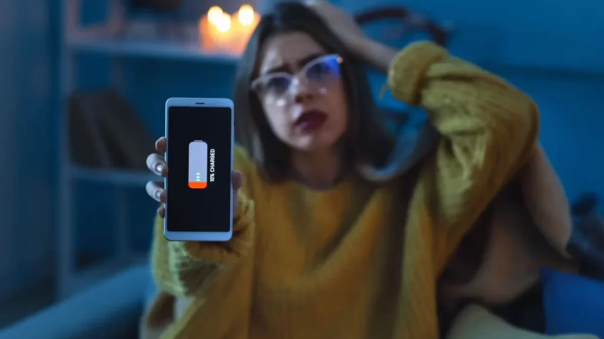 Mladá žena se skoro vybitým telefonem