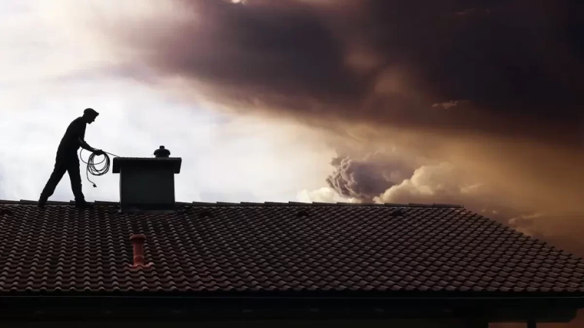 Kominík na střeše čistí komín