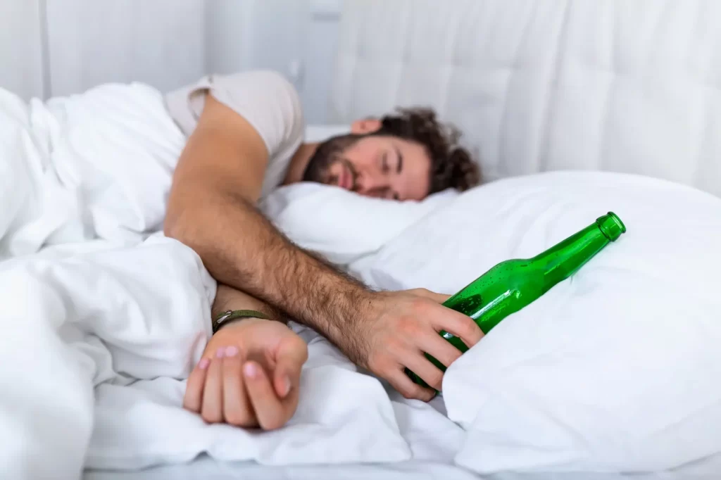 Shutterstock_1596962563 - SportDeník Muž spící s lahví od alkoholu v ruce