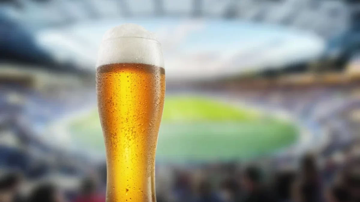 Půllitr piva s fotbalovým stadionem v pozadí