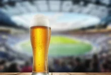 Půllitr piva s fotbalovým stadionem v pozadí