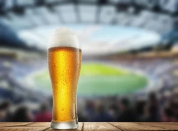 Půllitr piva s fotbalovým stadionem v pozadí