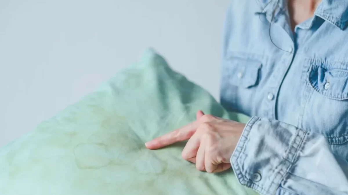 Žena ukazující na žluté skvrny na polštáři