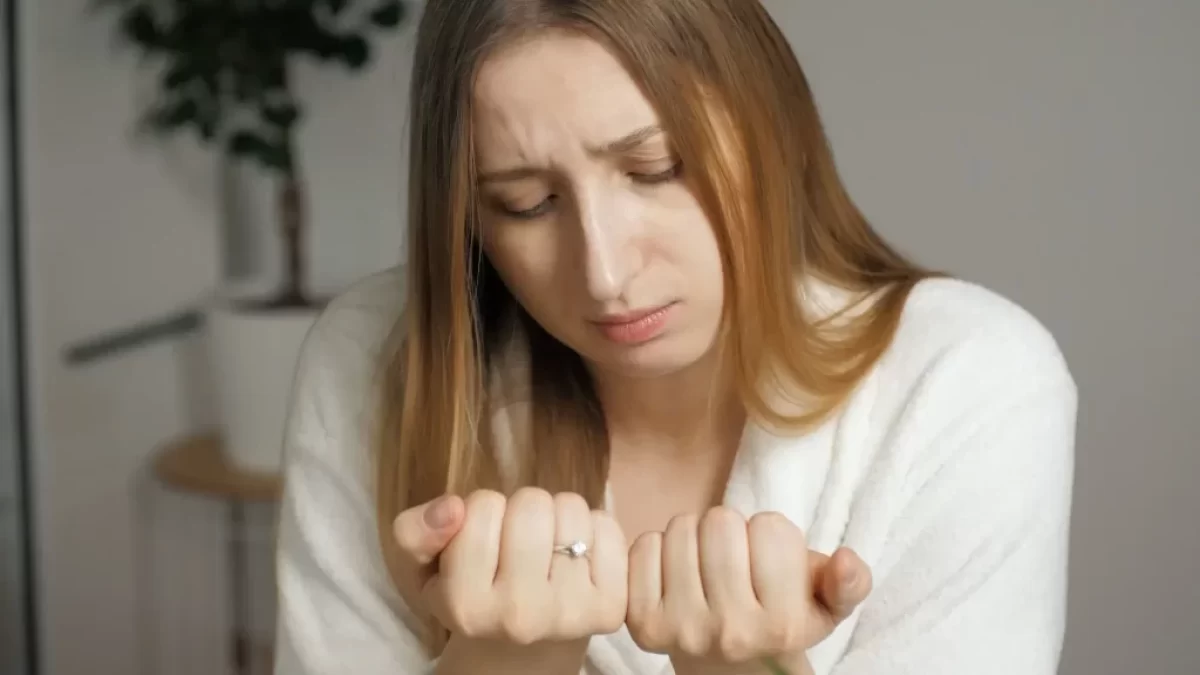 Žena se dívá na své nehty
