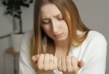 Žena se dívá na své nehty