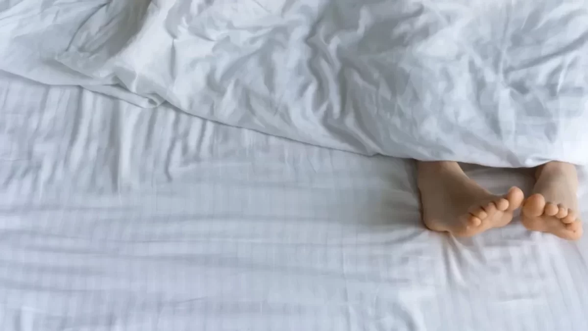 Dvě nohy koukající zpod peřiny