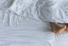 Dvě nohy koukající zpod peřiny