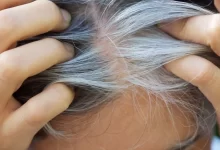 starší žena projíždějící prsty ve svých šedivých vlasech