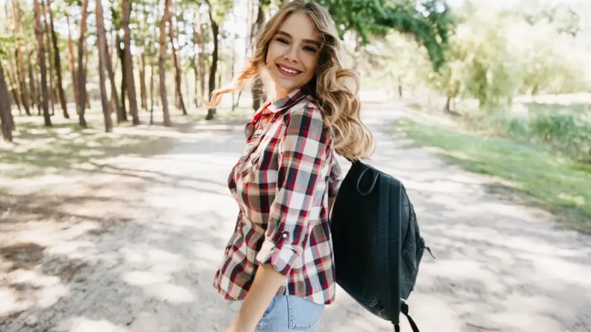 Mladá žena na vycházce v přírodě. Usmívá se.