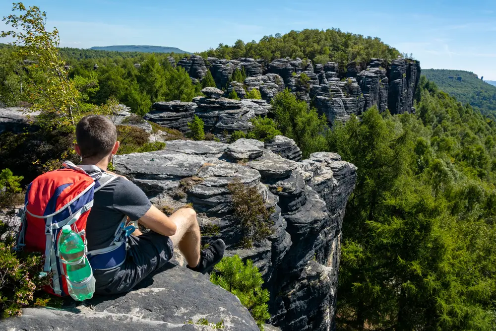 shutterstock_1673114752 - SportDeník Turista, který se nachází na vrcholu skalní stěny v Českém Švýcarsku.