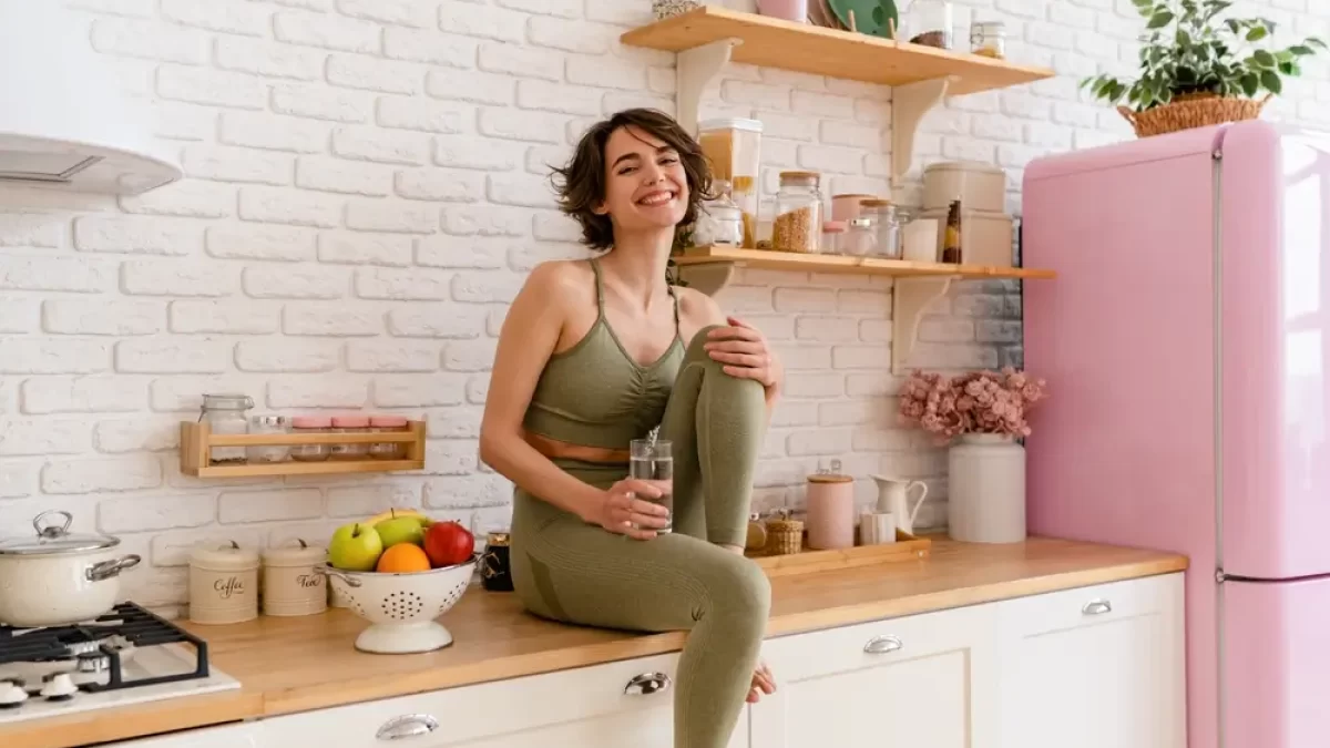 Mladá zdravá žena sedí na lince v kuchyni.
