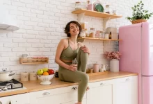 Mladá zdravá žena sedí na lince v kuchyni.