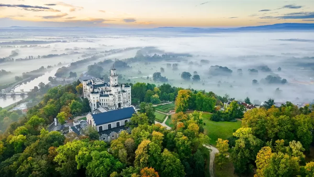 Hluboká nad Vltavou z leteckého pohledu. Okolní krajinu zahaluje mlha.