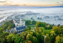 Hluboká nad Vltavou z leteckého pohledu. Okolní krajinu zahaluje mlha.