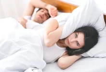 Pár v ložnici, žena si zacpává uši