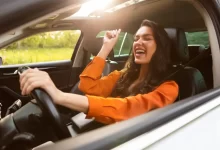 Žena sedí v autě za volantem a usmívá se.
