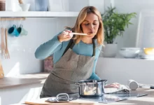 Žena ochutnává jídlo z hrnce.