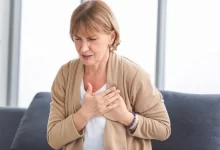 žena, která sedí na sedačce a drží si obě ruce na srdci.