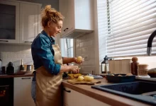 Žena loupe brambory u kuchyňské linky.