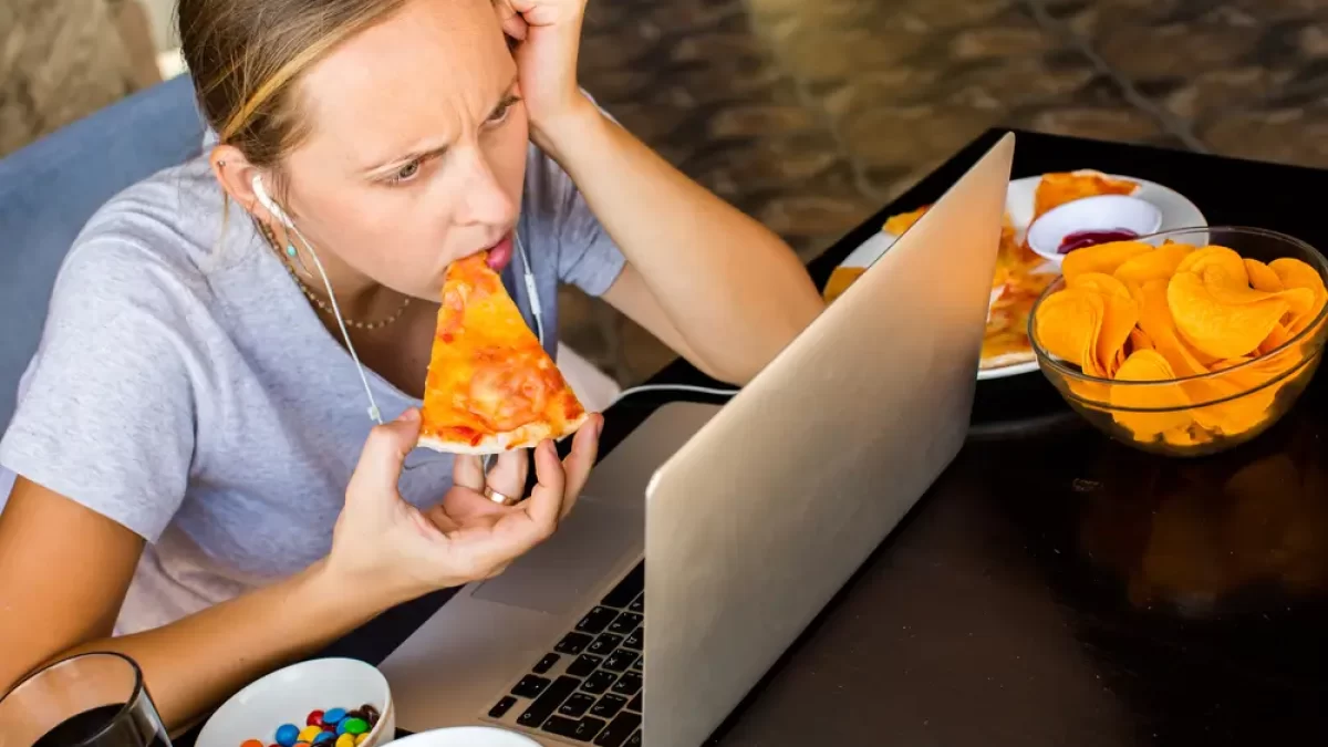 Žena u počítače pojídající pizzu