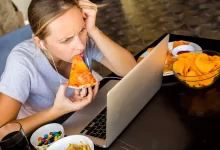 Žena u počítače pojídající pizzu